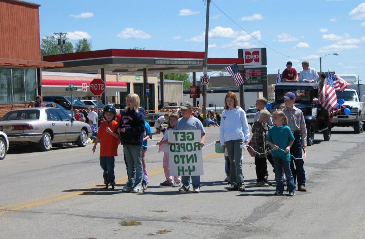 group of youth walking in a parade holding sign that reads get roped into 4-H